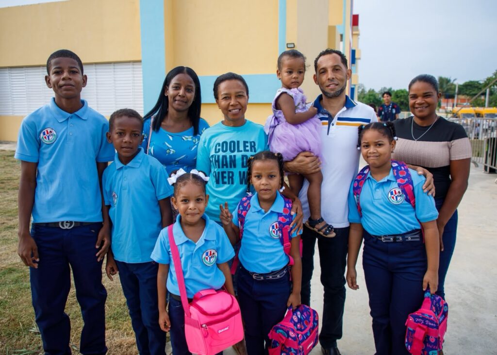 Grupo de adultos, jóvenes y niños uniformados en los terrenos de la Escuela Básica Espejo La Milagrosa.