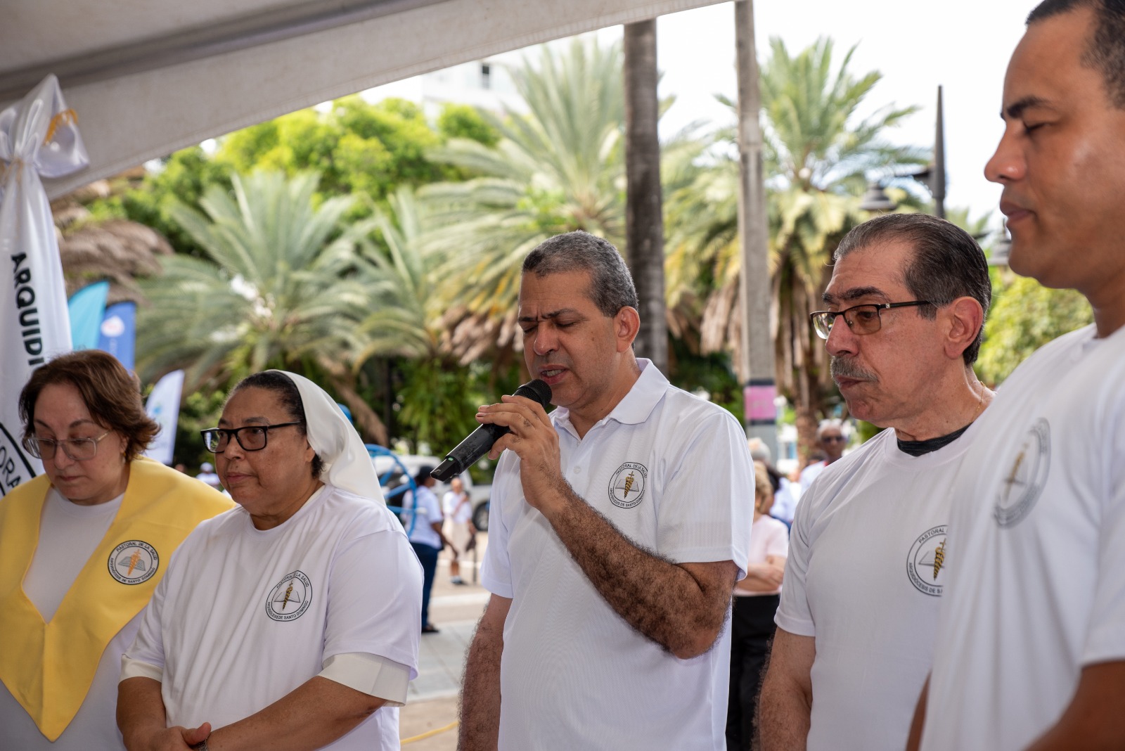 Monseñor Carlos Tomás Morel Diplán habla al micrófono acompañado por representantes de la Pastoral de la Salud.